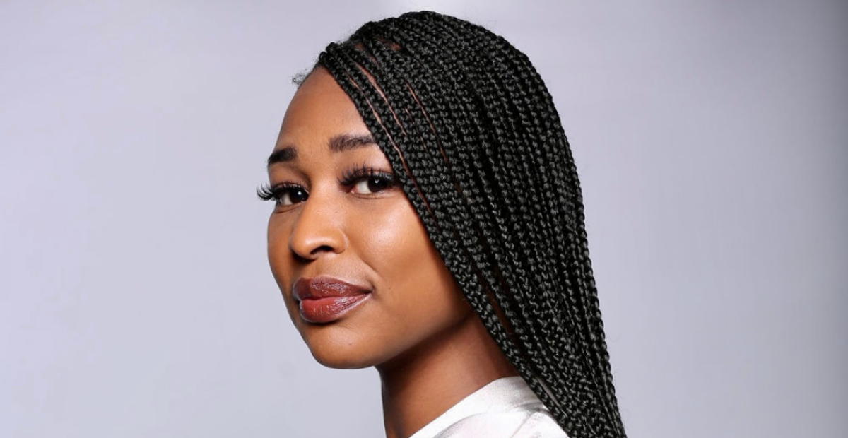 Close up of a woman wearing braids and smiling towards the camera