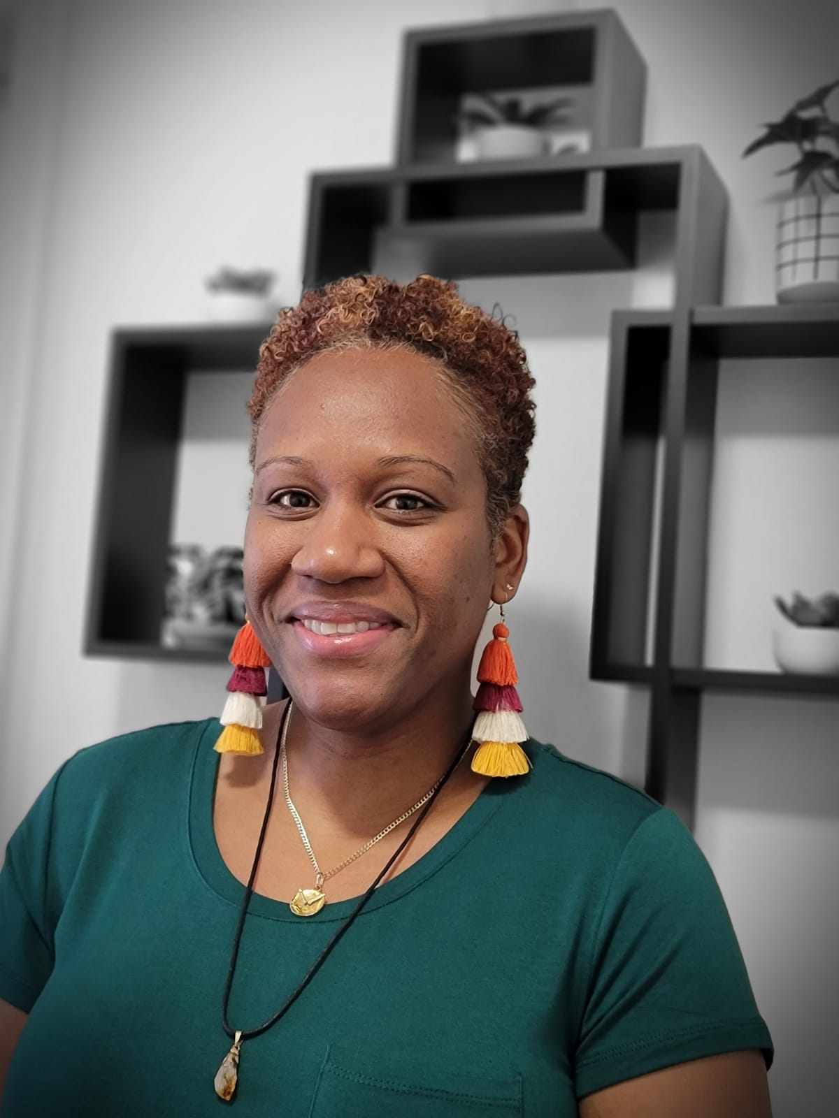 CEO of Maniyah's Blend with a black and white background with a green shot sleeved shirt and yellow and red earrings