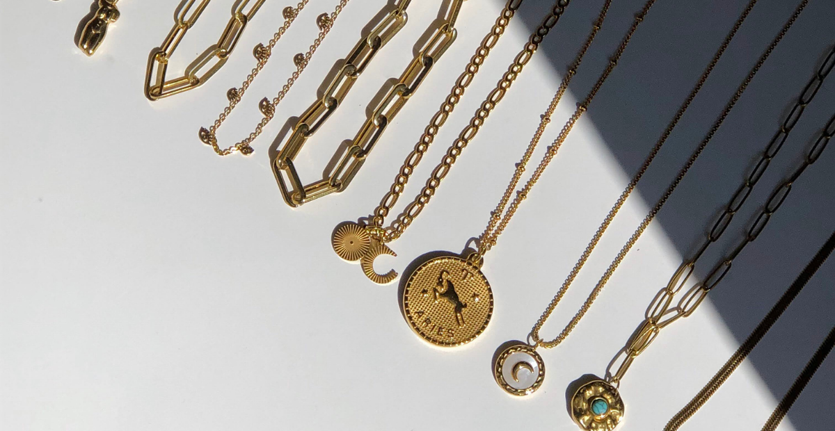A number of necklaces on a white flatlay with a dark shadow hovering over some of the necklaces
